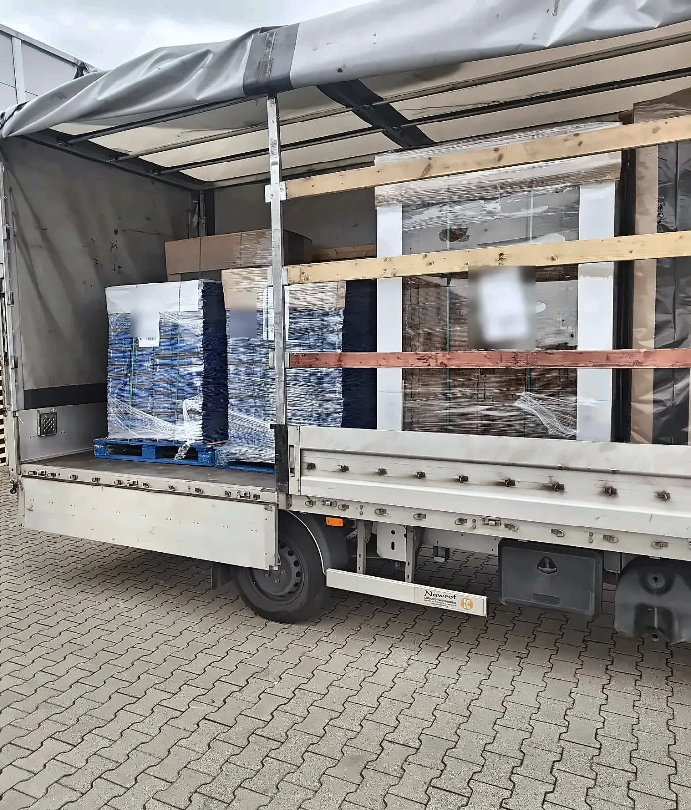 Bus Taleron z odsuniętą plandeką podczas załadunku palet